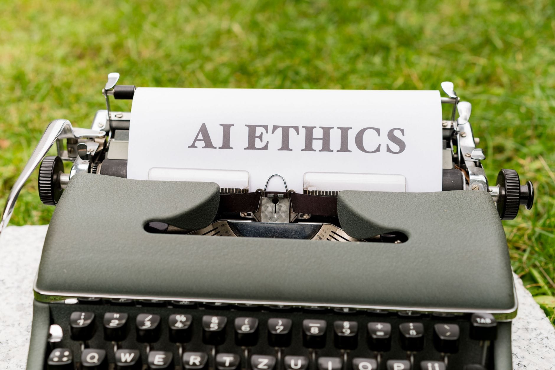 Stara maszyna do pisania na zewnątrz z kartką z napisem AI ethics
