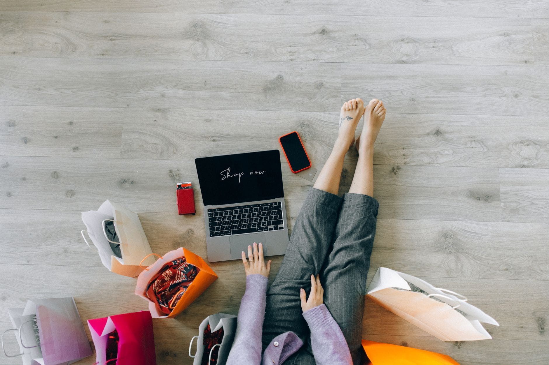Kobieta robi zakupy online na laptopie, obok papierowe torby