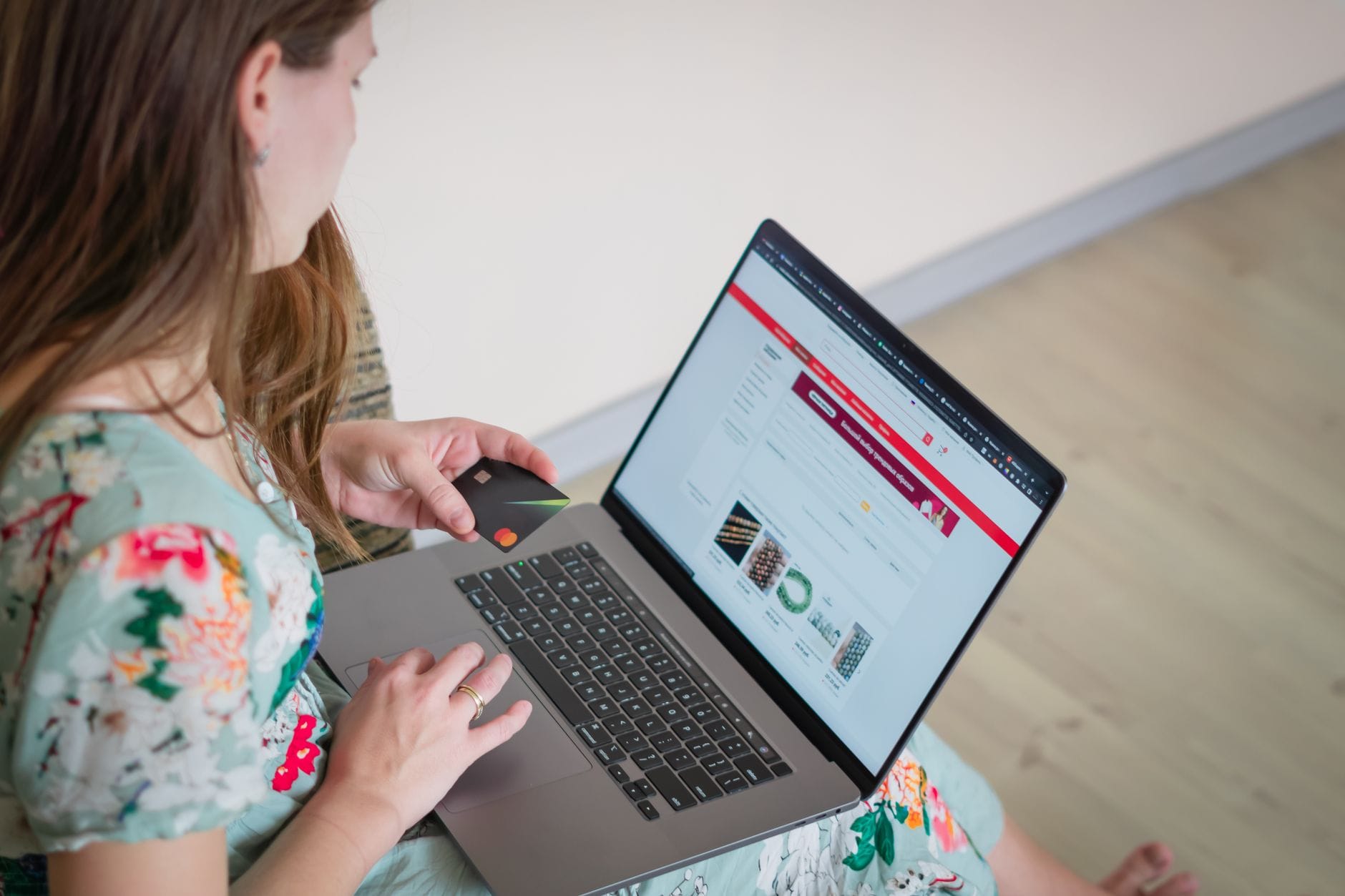 Jak kupować świadomie i oszczędnie: praktyczny przewodnik po bezpiecznych zakupach online i stacjonarnych Kobieta w kwiecistej sukience robiąca zakupy online na laptopie